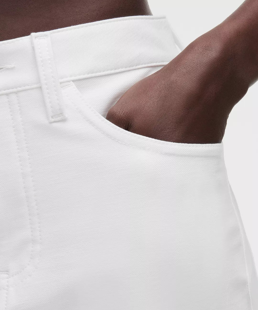 Close-up of a person wearing white pants with a neutral background