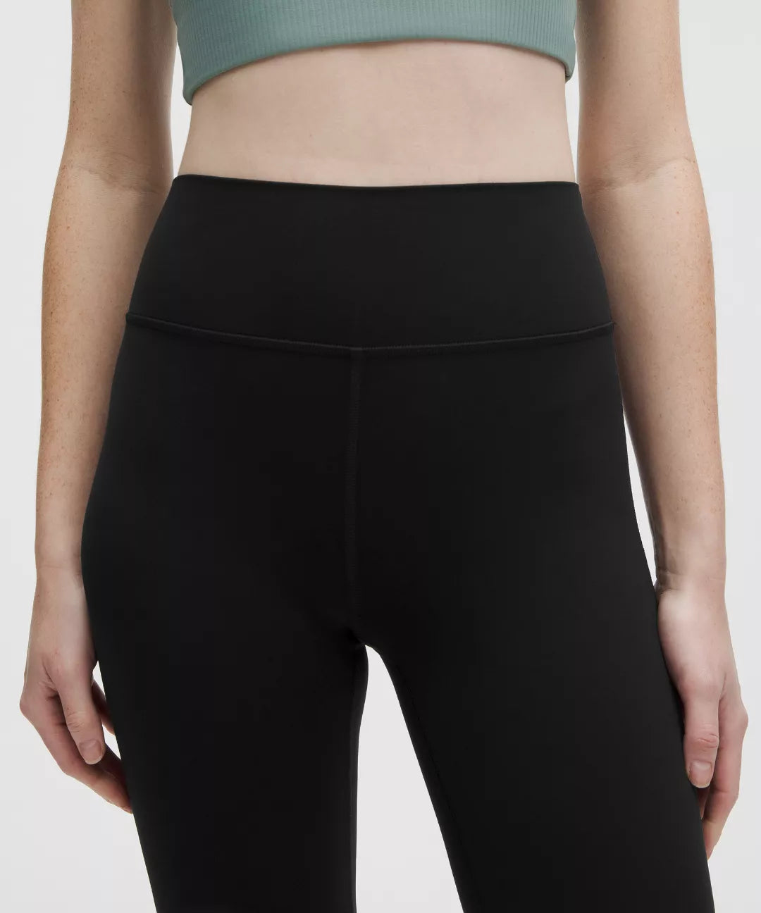 Person wearing black leggings on a plain background