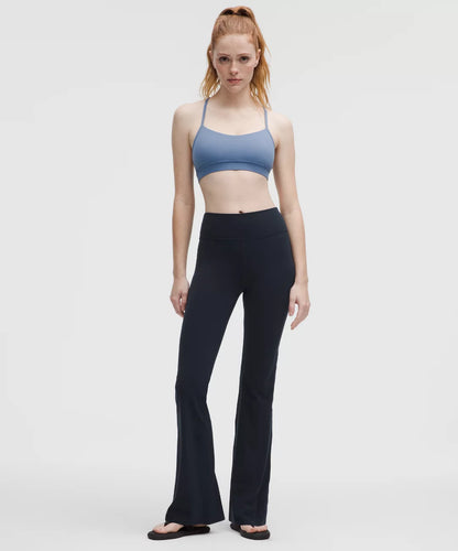 Woman wearing a blue sports bra and black leggings on a white background