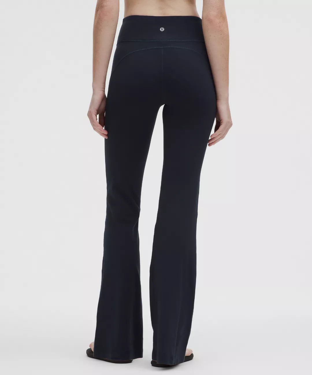 Person wearing black flared pants on a white background