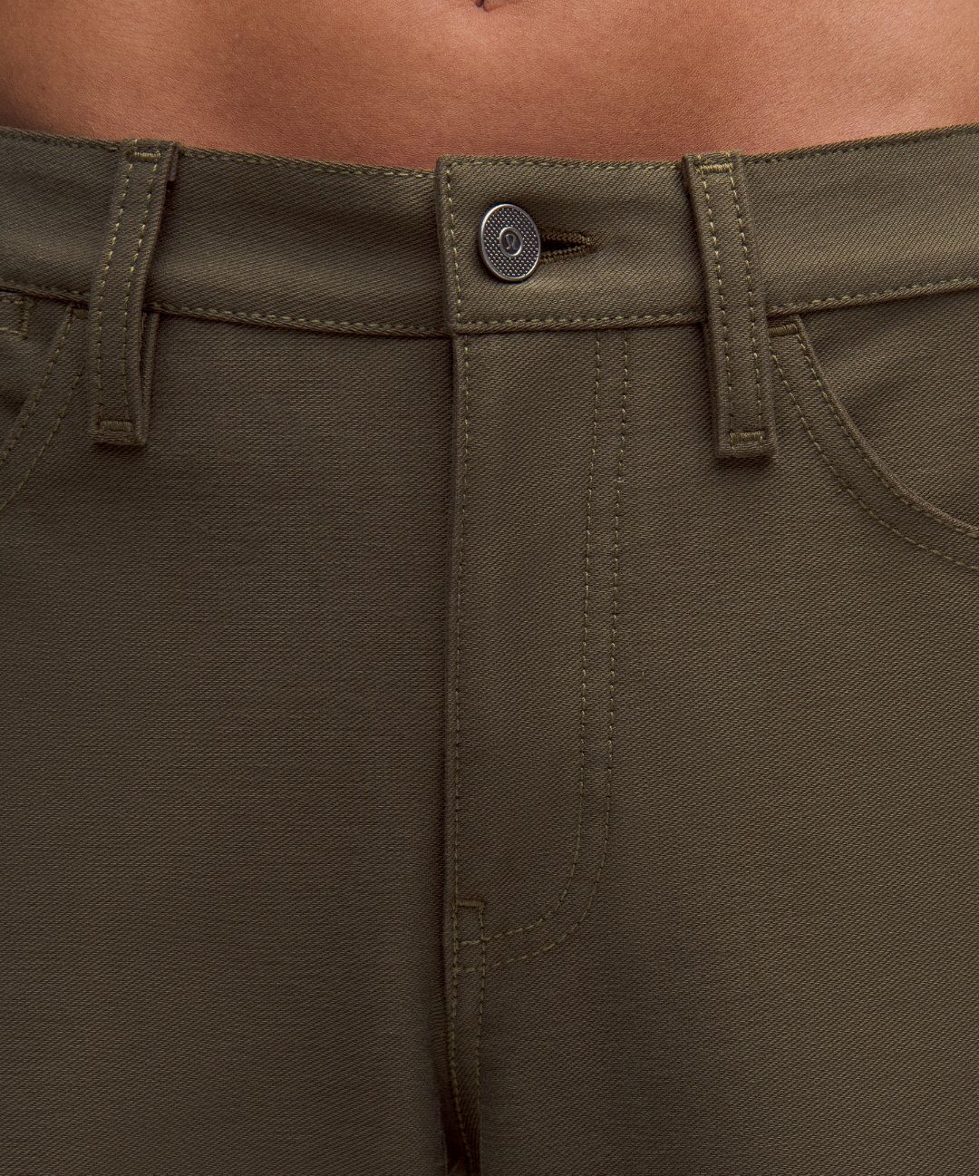 Close-up of olive green pants with a button detail.