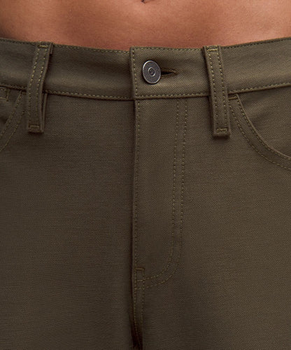 Close-up of olive green pants with a button detail.