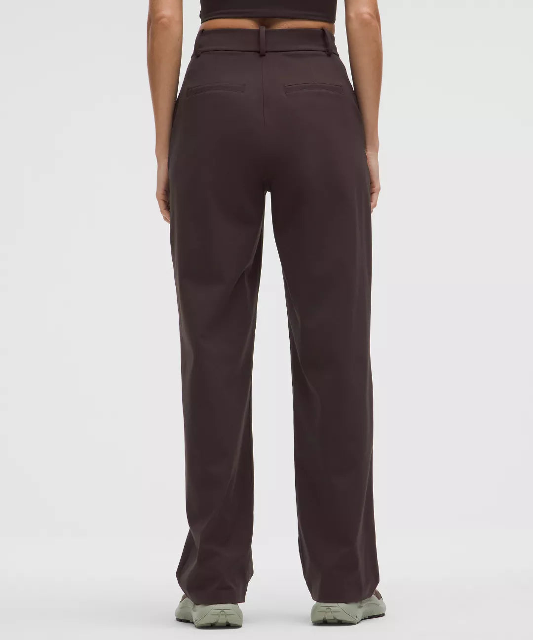 Dark brown pants worn by a person on a white background