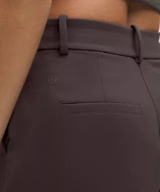 Brown pants with a logo on the pocket against a beige background