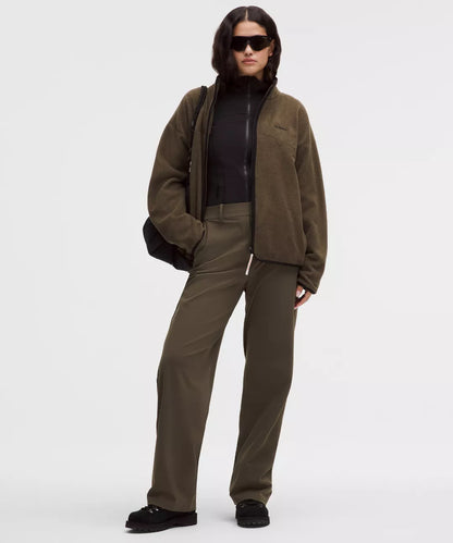 Person wearing a brown jacket and pants with a black shirt underneath on a white background
