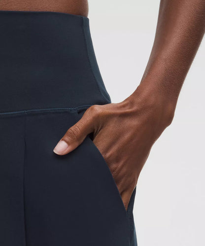 Person wearing dark blue pants with a hand in the pocket against a light background
