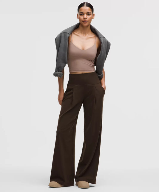 Woman wearing a gray cardigan, beige top, and brown wide-leg pants on a white background