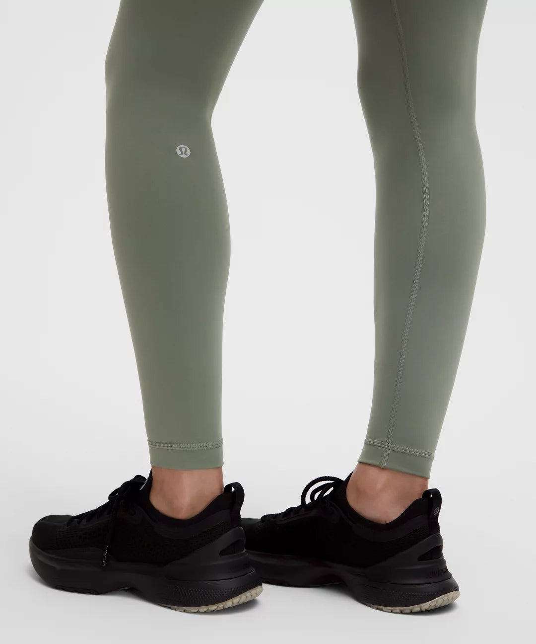 Green leggings worn by a person with black sneakers on a white background