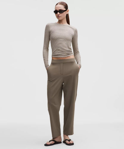 Woman wearing a beige long-sleeve top and pants on a white background