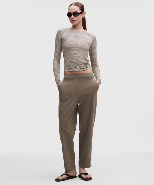 Woman wearing a beige long-sleeve top and pants on a white background