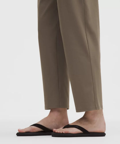 Person wearing beige pants and black sandals on a white background