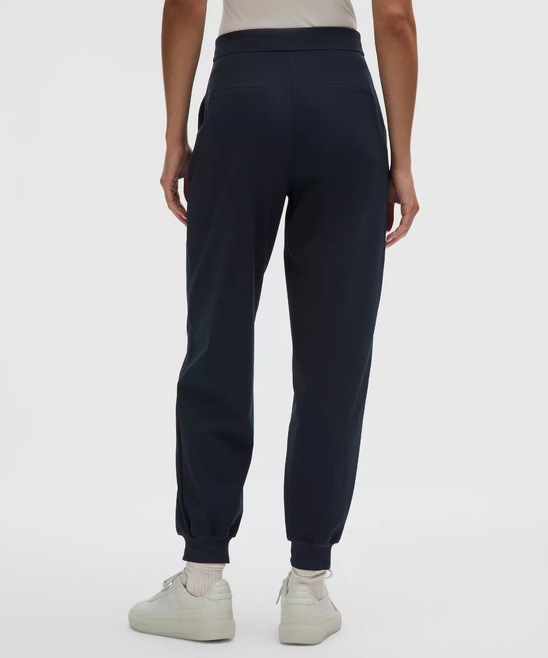 Navy blue jogger pants worn by a person on a white background