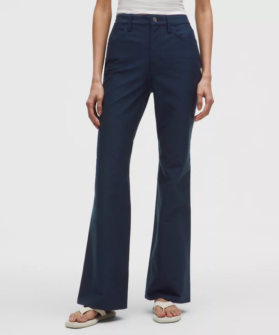 Navy blue flared pants worn by a person on a white background