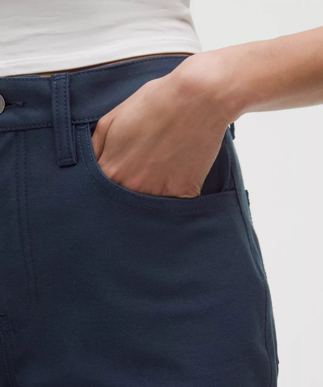 Navy blue pants with a hand in the pocket on a light gray background