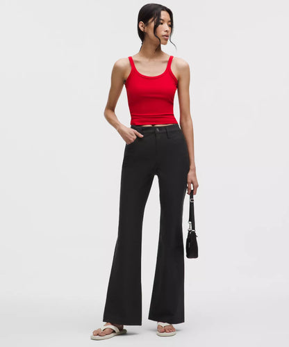 Woman wearing a red tank top and black flared pants on a white background