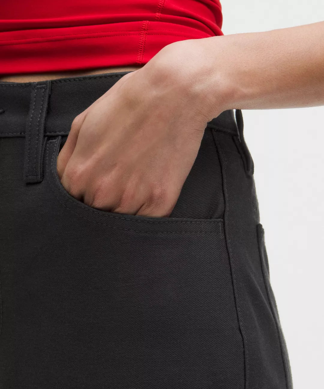 Person wearing black pants with a red top, hand in pocket