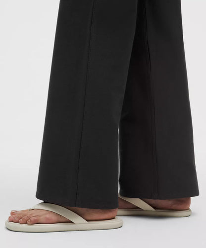 Person wearing black wide-leg pants and beige sandals on a white background