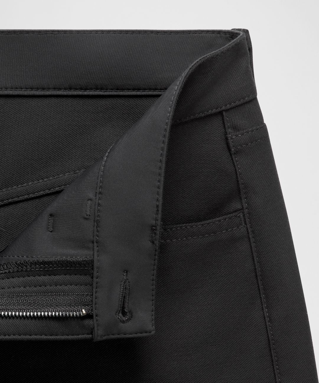 Close-up of a black jacket with zippers and buttons on a light gray background