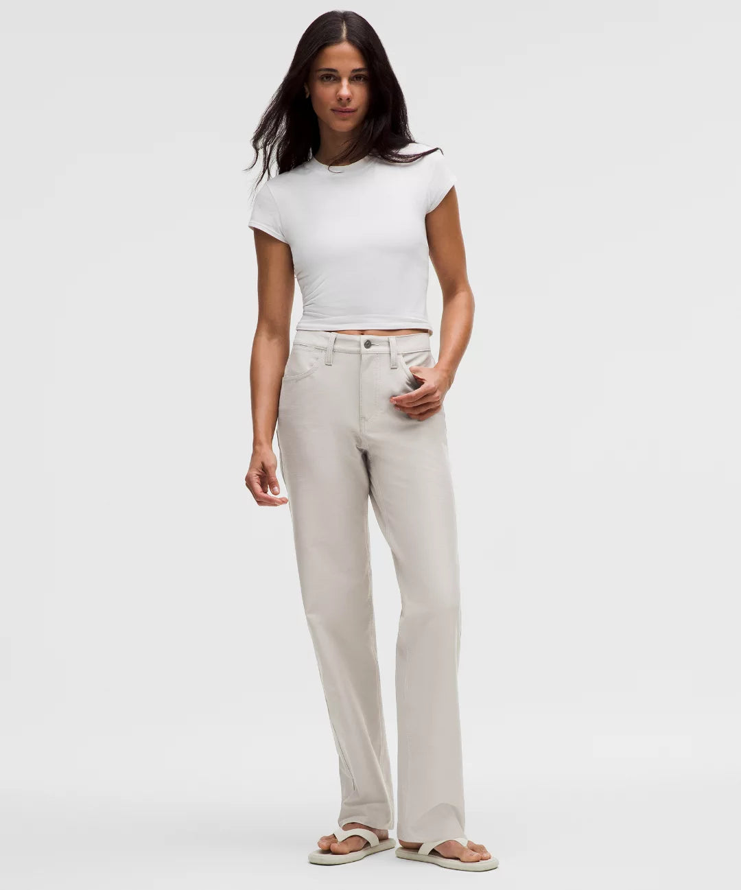 Woman wearing a white t-shirt and beige pants on a white background