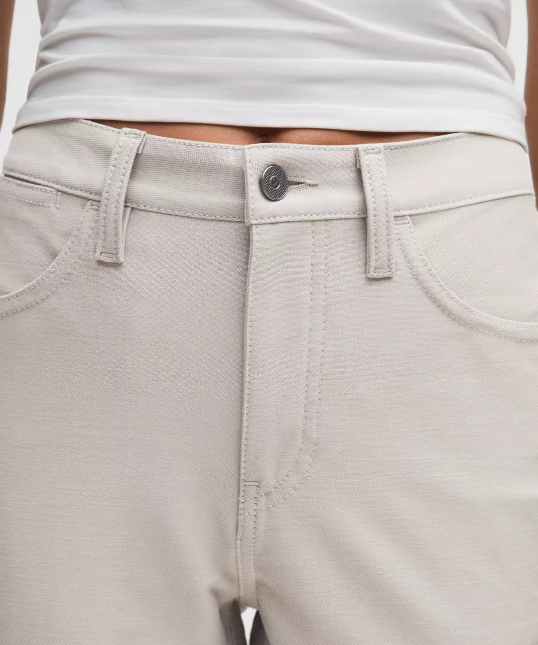 Close-up of light gray pants with a button and stitching details.