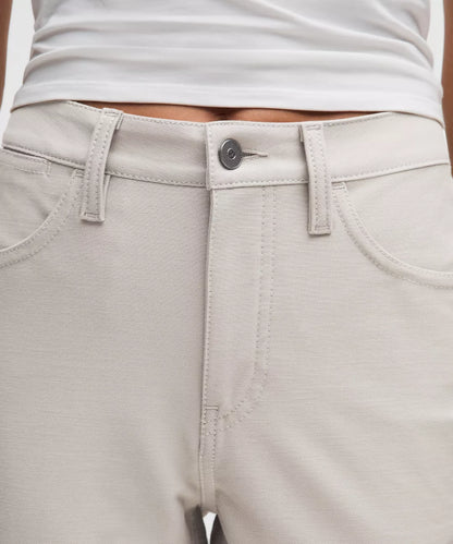 Close-up of light gray pants with a button and stitching details.
