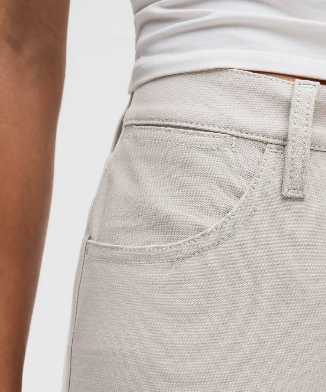 Close-up of light gray pants with a white shirt underneath