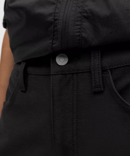 Close-up of a black garment with a button and belt detail