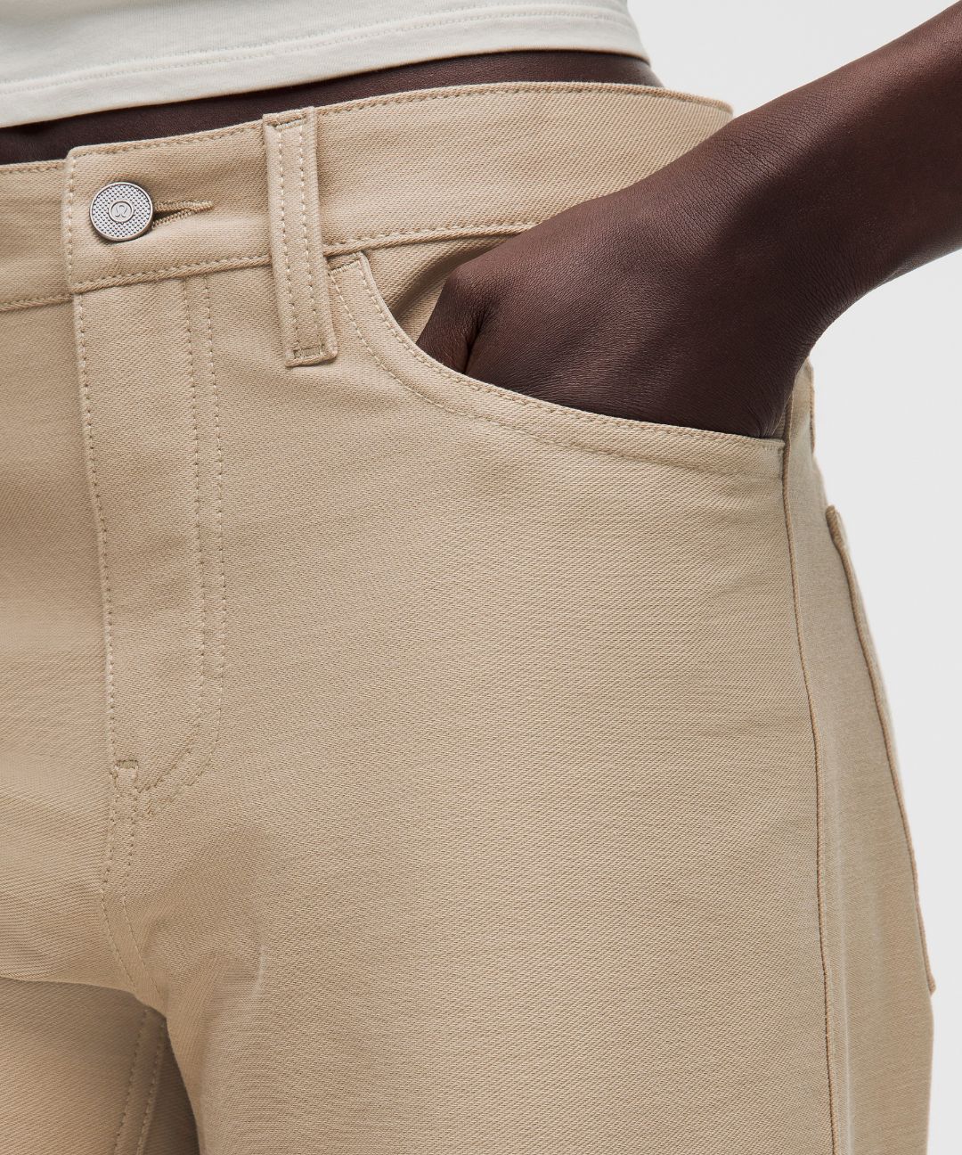 Close-up of beige pants with a button on a light gray background