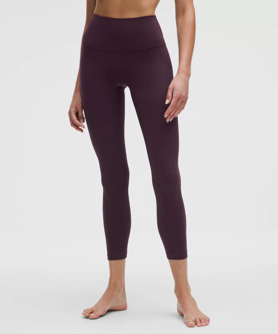 Person wearing dark purple leggings on a white background