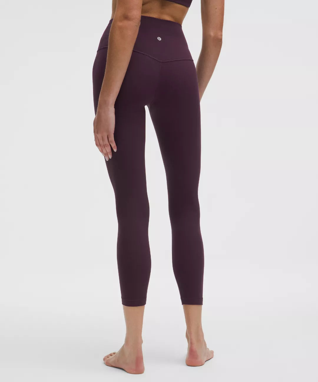 Person wearing dark purple leggings on a white background