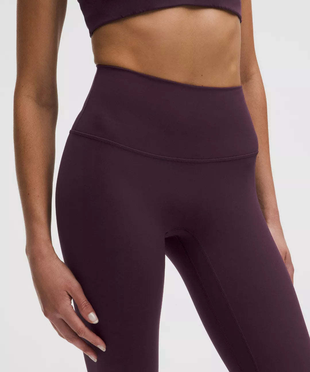 Purple athletic leggings worn by a person on a light gray background
