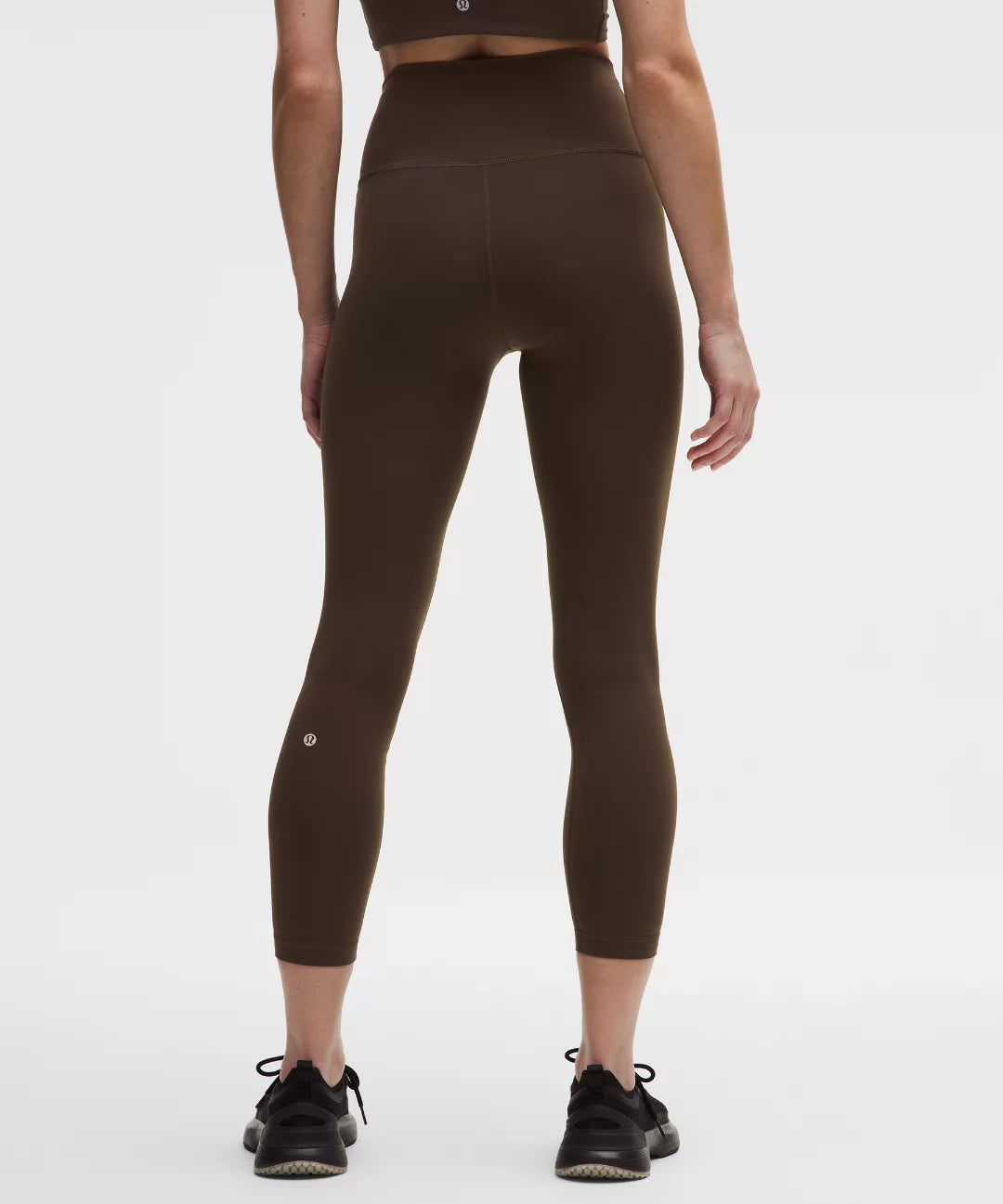Person wearing brown high-waisted leggings on a white background