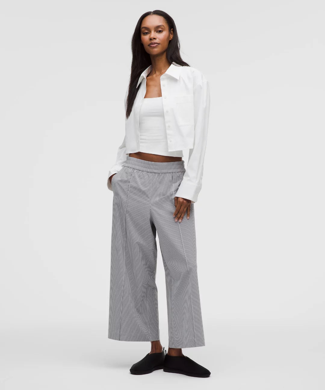 Woman wearing a white blouse and gray pants on a white background