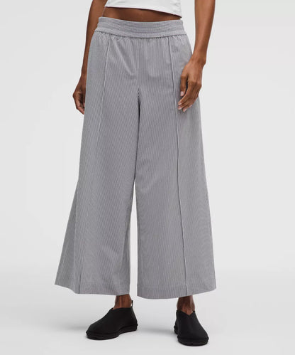 Person wearing gray checkered wide-leg pants on a white background