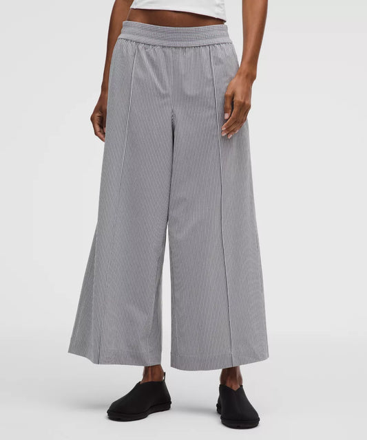 Person wearing gray checkered wide-leg pants on a white background