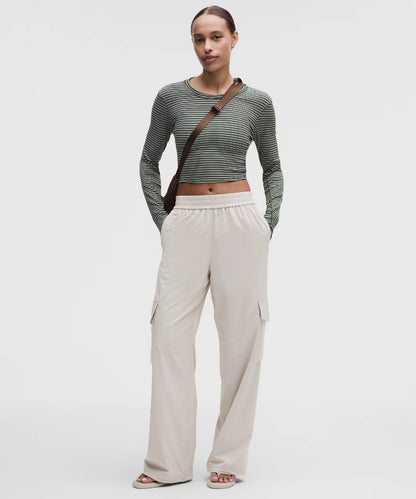 Woman wearing a striped long-sleeve top and beige wide-leg pants on a white background