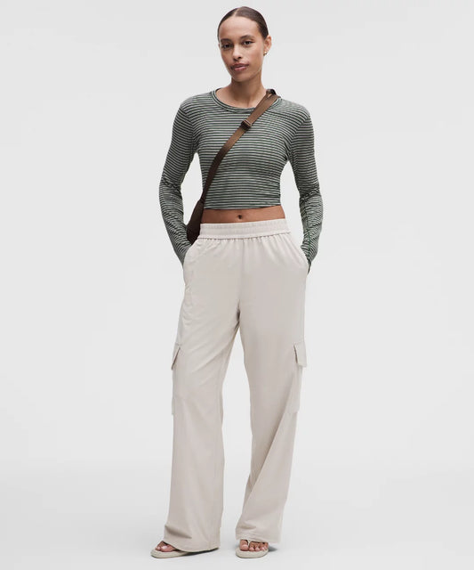 Woman wearing a striped long-sleeve top and beige wide-leg pants on a white background