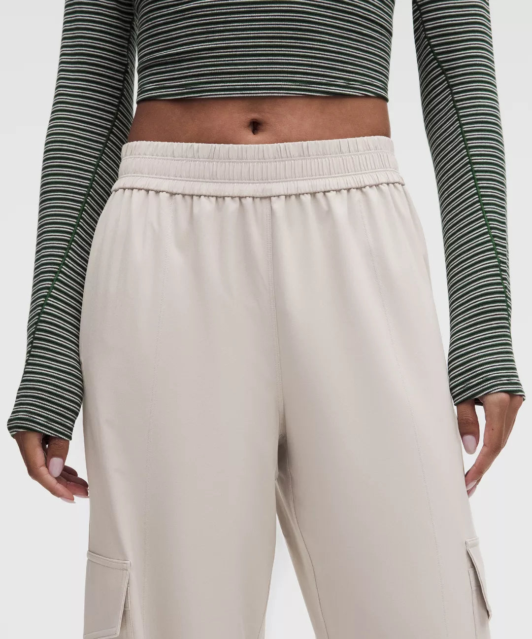Person wearing a striped long-sleeve top and beige pants on a white background