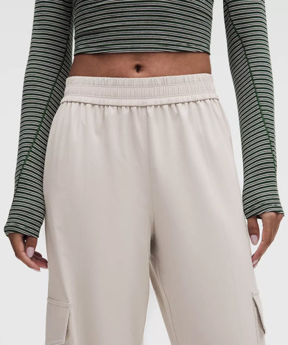 Person wearing a striped long-sleeve top and beige pants on a white background