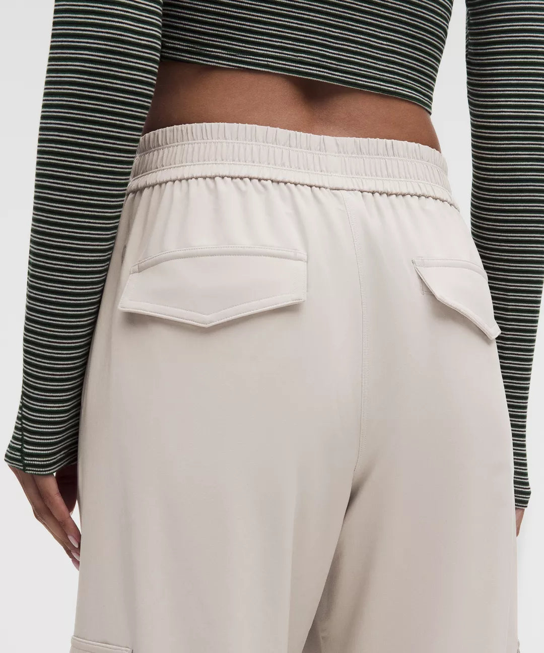 Beige pants worn with a striped long-sleeve top on a plain background