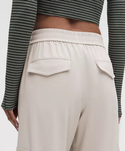 Beige pants worn with a striped long-sleeve top on a plain background