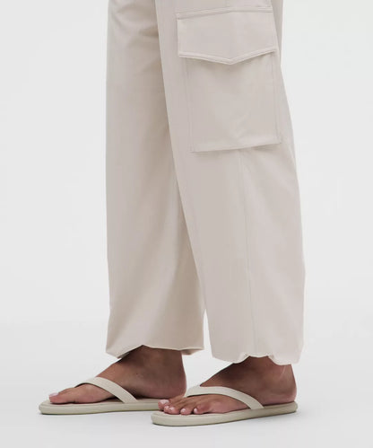 Person wearing beige sandals and light-colored pants on a white background