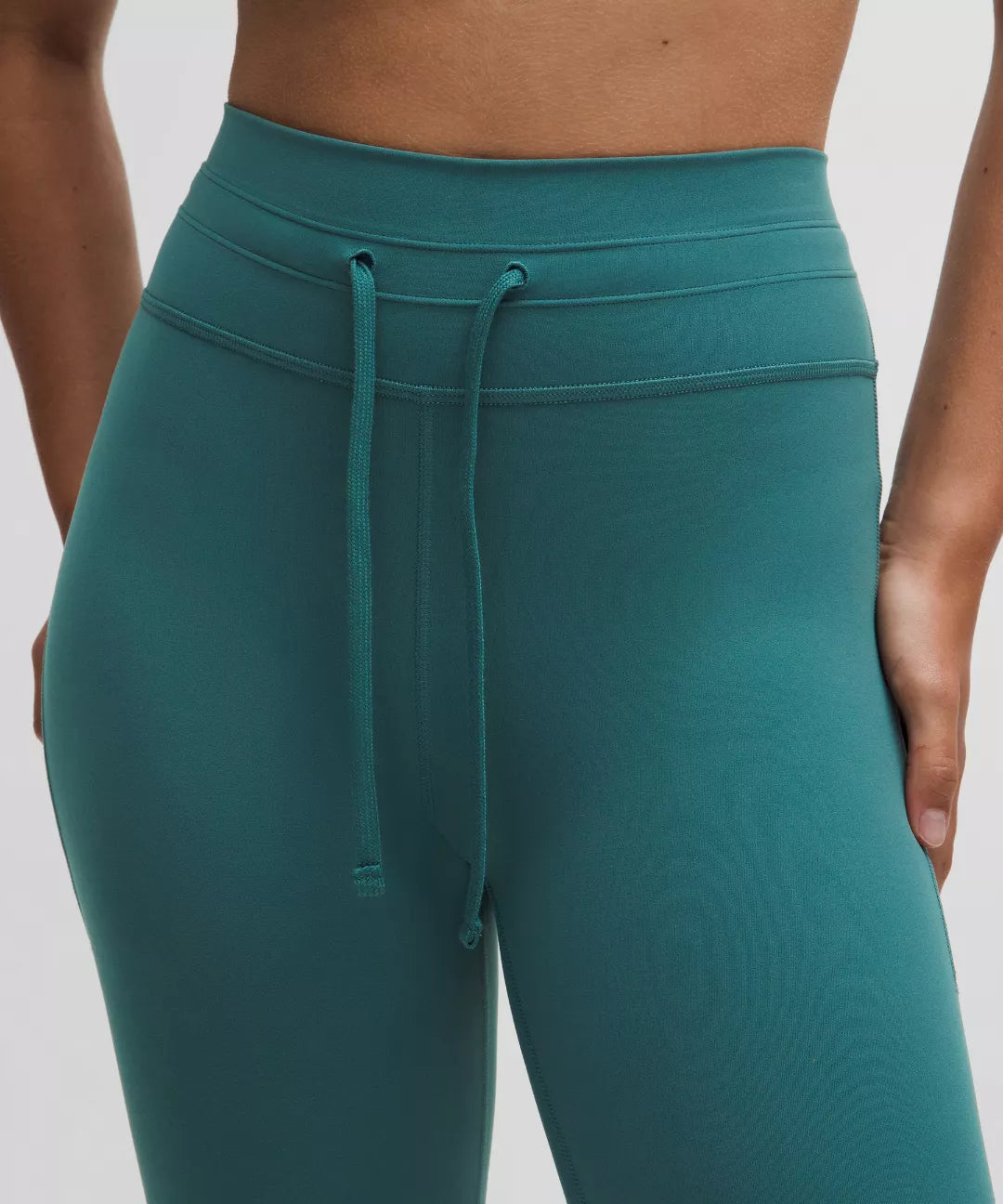 Teal leggings with a drawstring waistband on a white background