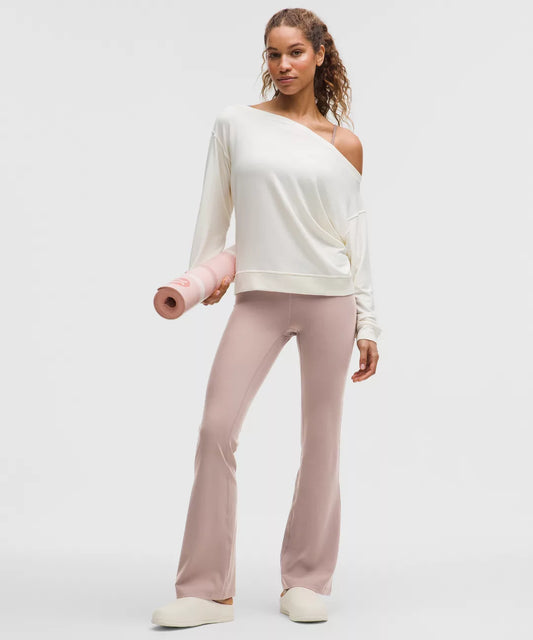 Woman holding a pink yoga mat wearing a white top and pink pants on a light gray background