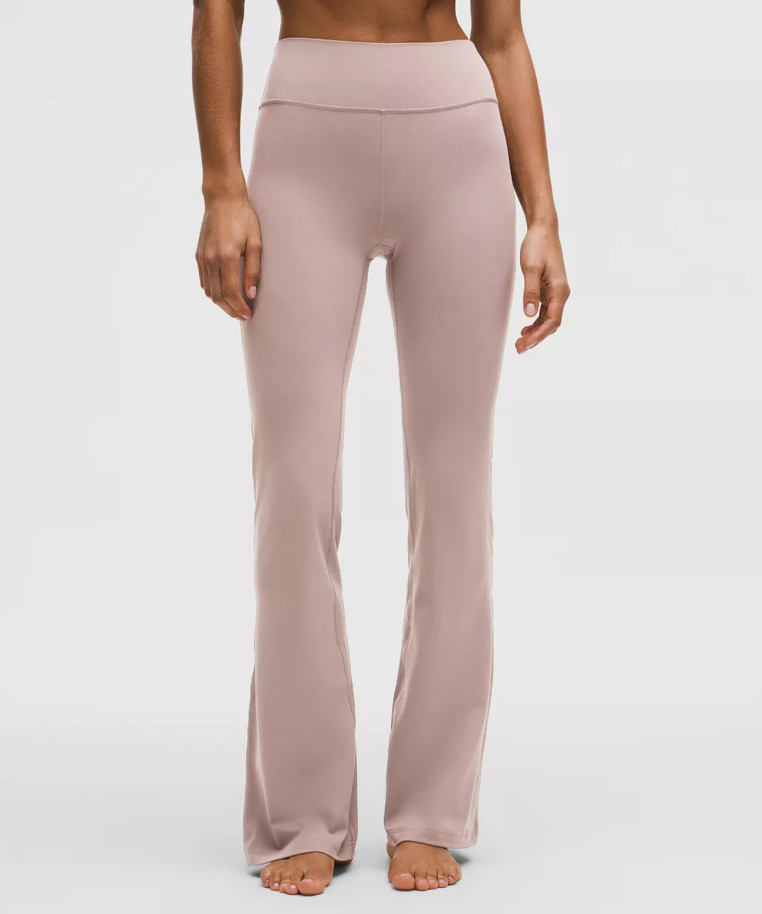 Person wearing light pink high-waisted pants on a white background