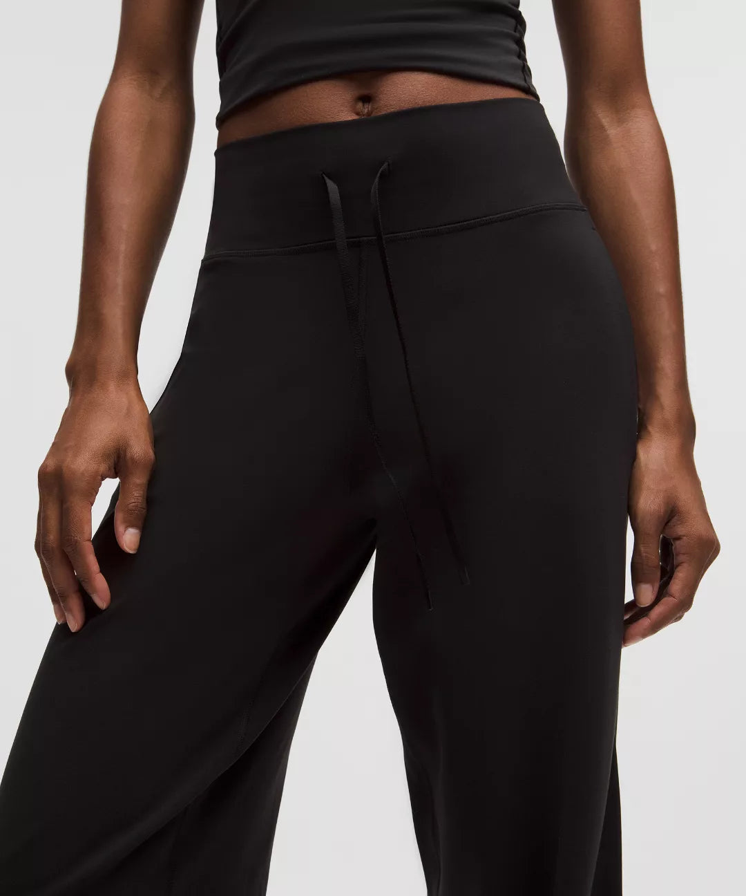 Person wearing black high-waisted pants on a light gray background