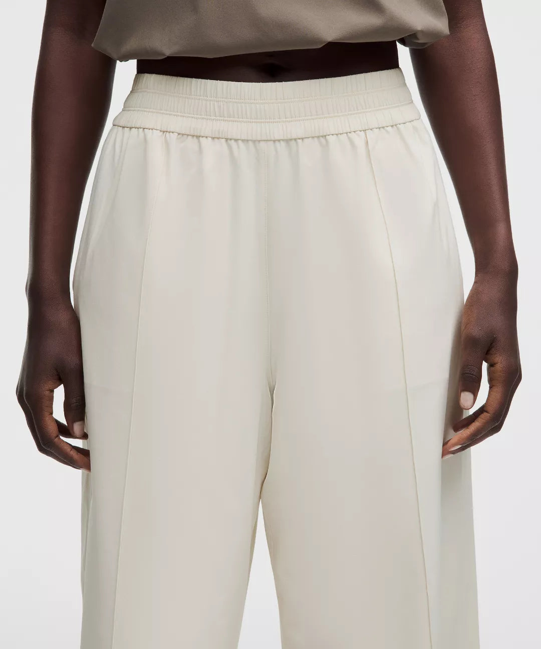 Beige pants worn by a person on a white background