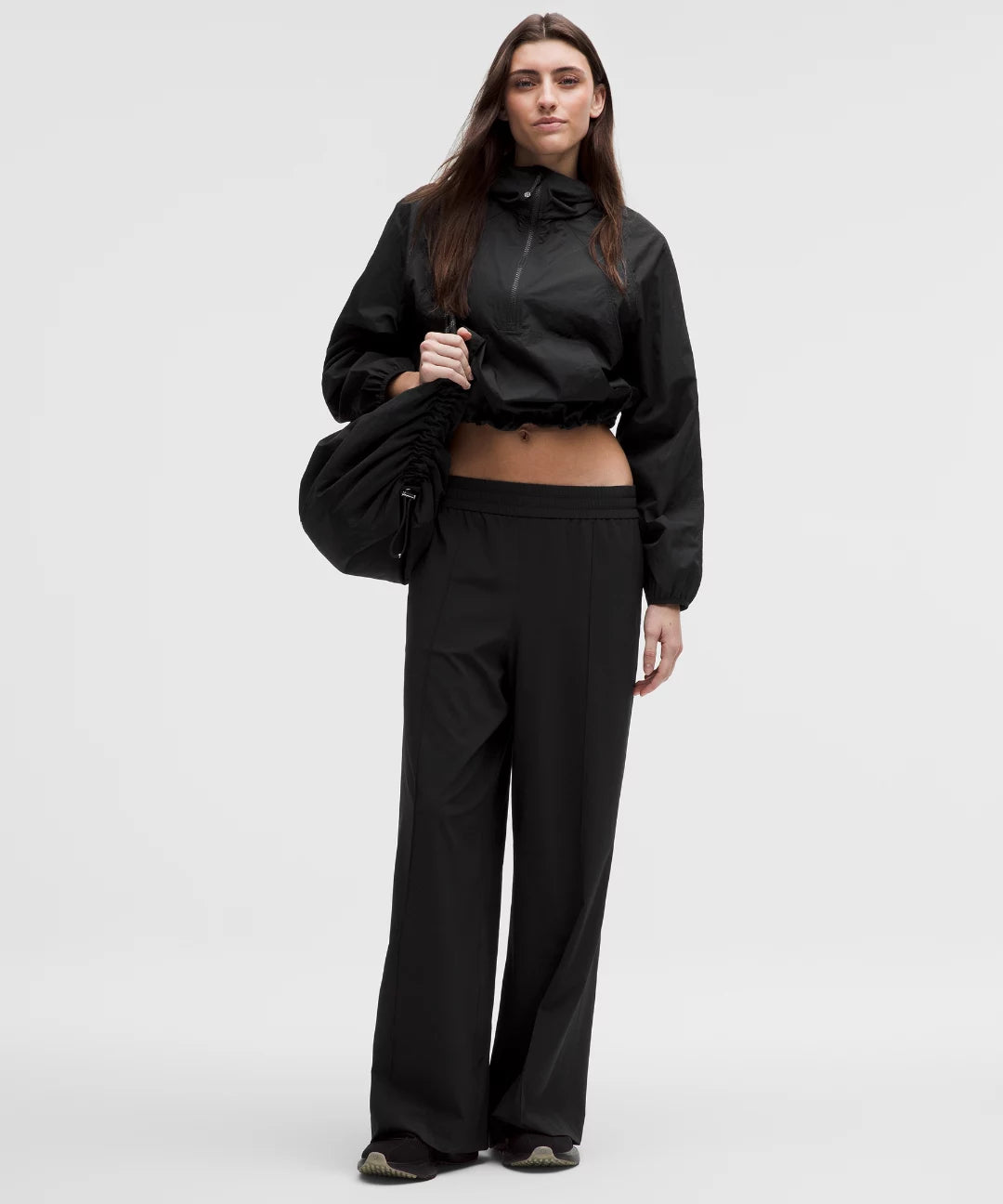 Person wearing a black outfit with a jacket and pants on a white background