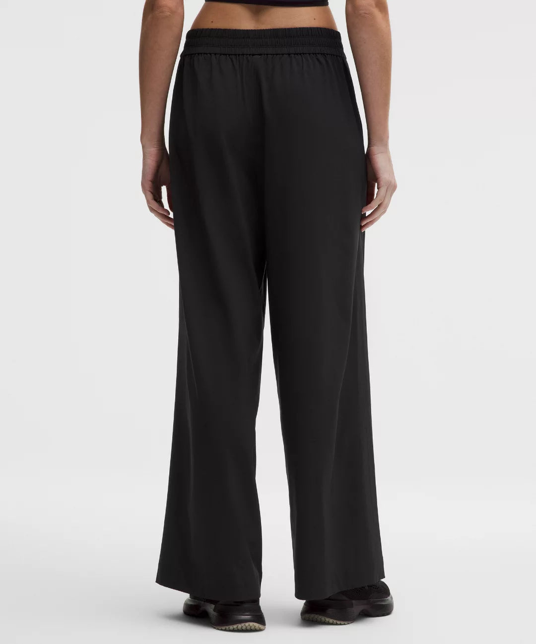 Person wearing black wide-leg pants on a white background