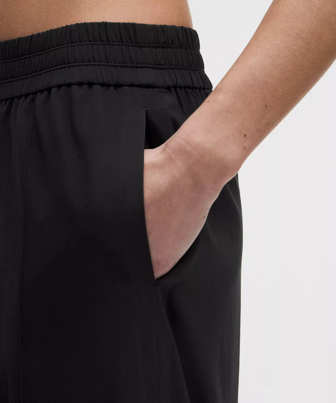 Person wearing black pants with a plain background